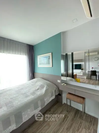 Modern bedroom with stylish decor and natural light, featuring a cozy bed and elegant vanity area.
