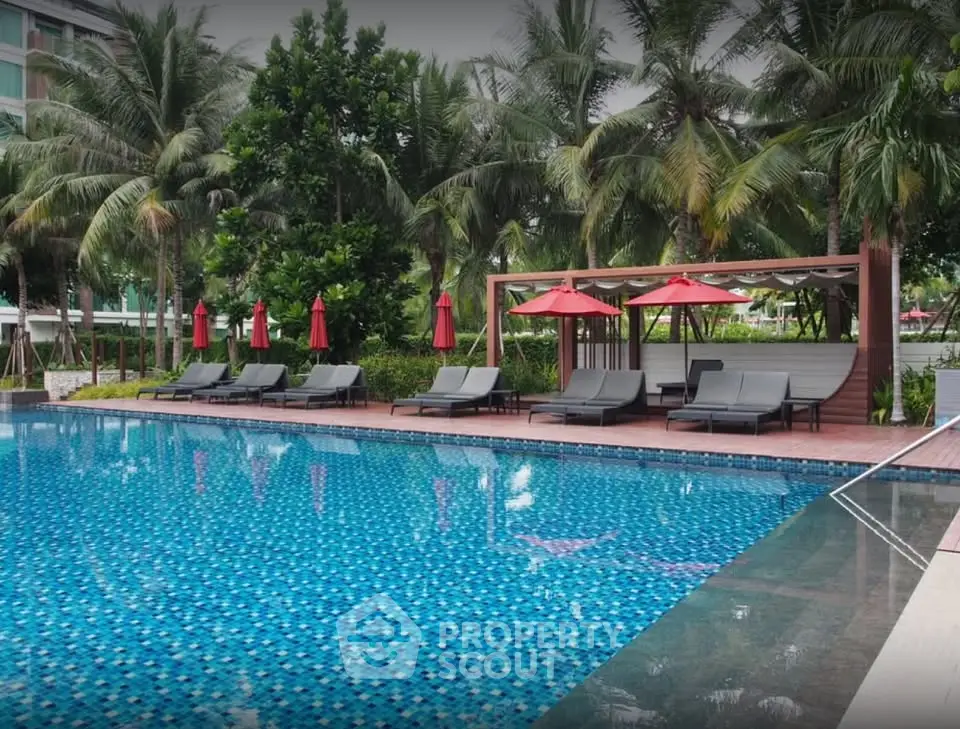 Luxurious poolside area with sun loungers and umbrellas in a tropical setting.