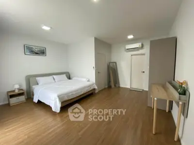 Spacious modern bedroom with wooden flooring and minimalist decor