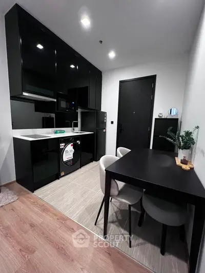 Modern kitchen with sleek black cabinets and dining area in stylish apartment