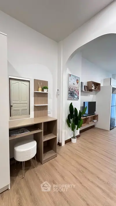 Modern living room with stylish decor and wooden flooring, featuring a cozy study nook and elegant shelving.