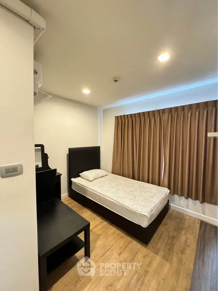 Cozy bedroom with single bed and wooden flooring, perfect for minimalist living.