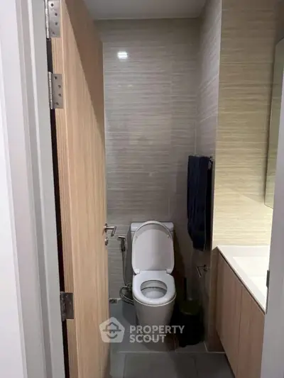Modern bathroom with sleek design and neutral tones, featuring a toilet and vanity.