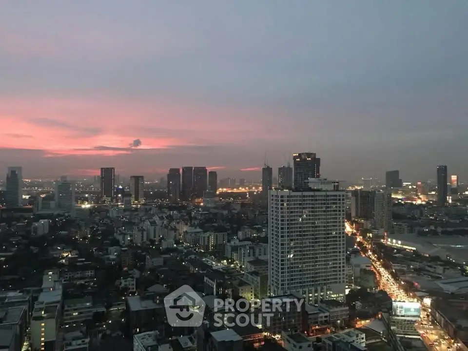 Stunning cityscape view at dusk with illuminated skyline and vibrant sunset hues.