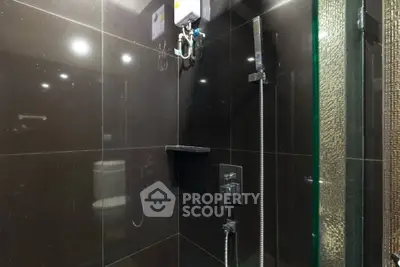 Modern bathroom with sleek black tiles and contemporary shower fixtures.