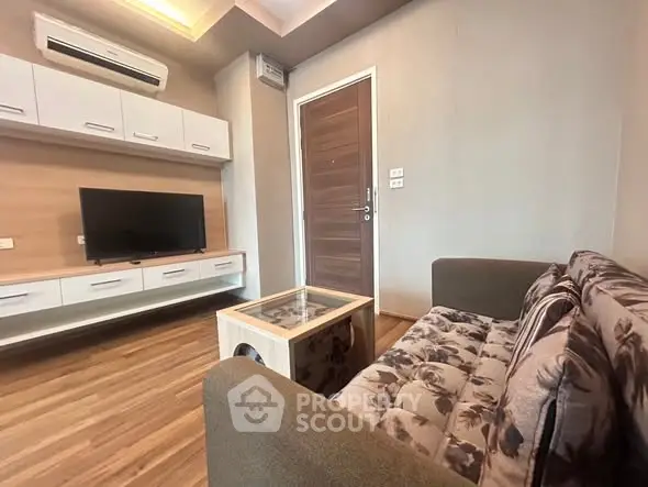 Modern living room with stylish furniture and wooden flooring, featuring a wall-mounted TV and air conditioning.