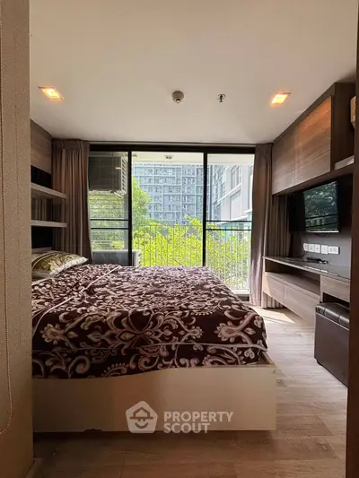 Modern bedroom with large window and city view, featuring stylish decor and ample natural light.