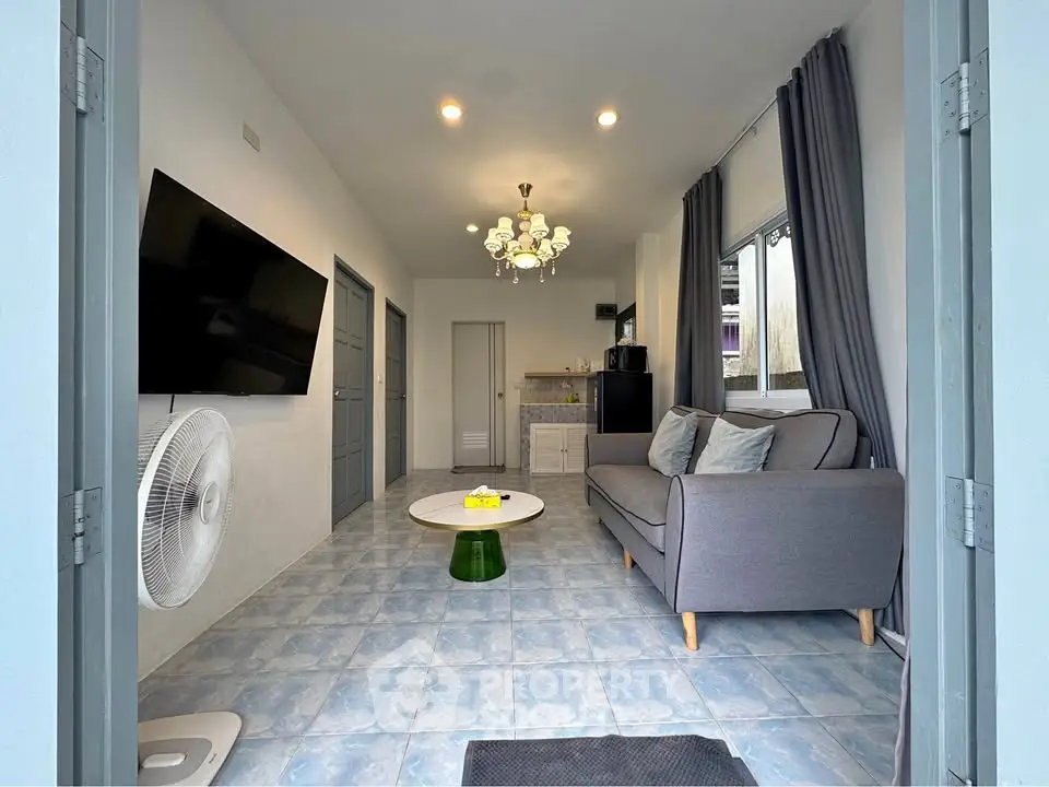 Modern living room with stylish decor, featuring a cozy sofa, wall-mounted TV, and elegant lighting.
