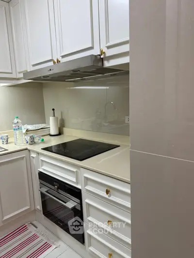 Modern kitchen with sleek cabinetry and built-in oven, featuring a clean and elegant design.