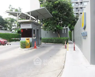 Modern building entrance with security booth and lush greenery