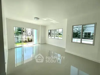 Spacious and bright living room with large windows and garden view, perfect for family gatherings.