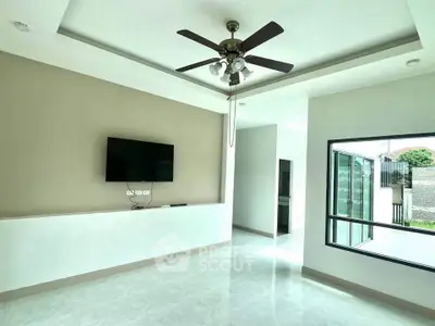 Modern living room with ceiling fan and wall-mounted TV, featuring large windows for natural light.