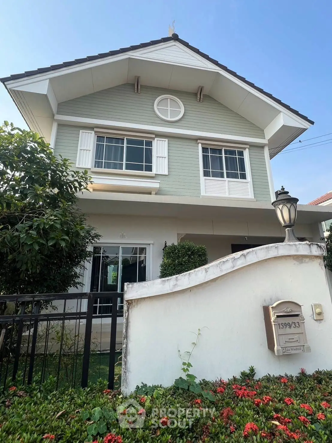 Charming two-story house with lush garden and classic architectural design.