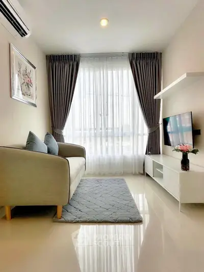 Modern living room with cozy sofa, stylish decor, and natural light from large window.