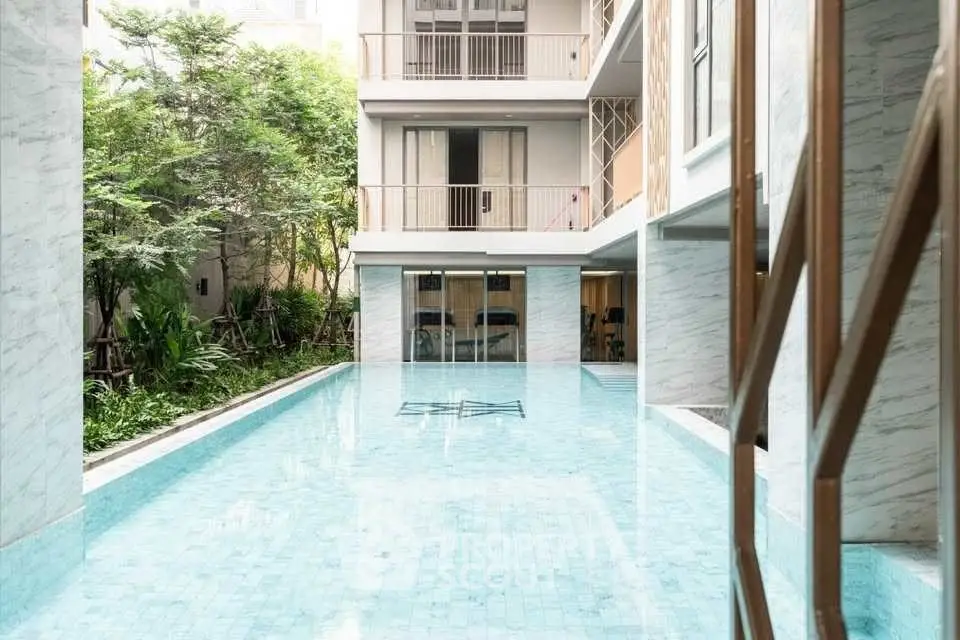 Luxurious residential building with serene pool and lush greenery