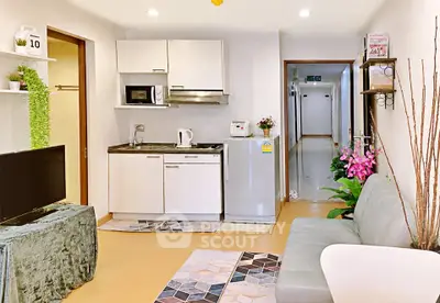 Modern studio apartment with cozy living area and compact kitchen featuring microwave and fridge.
