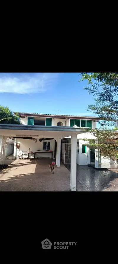 Charming two-story house with spacious patio and lush greenery, perfect for family living.