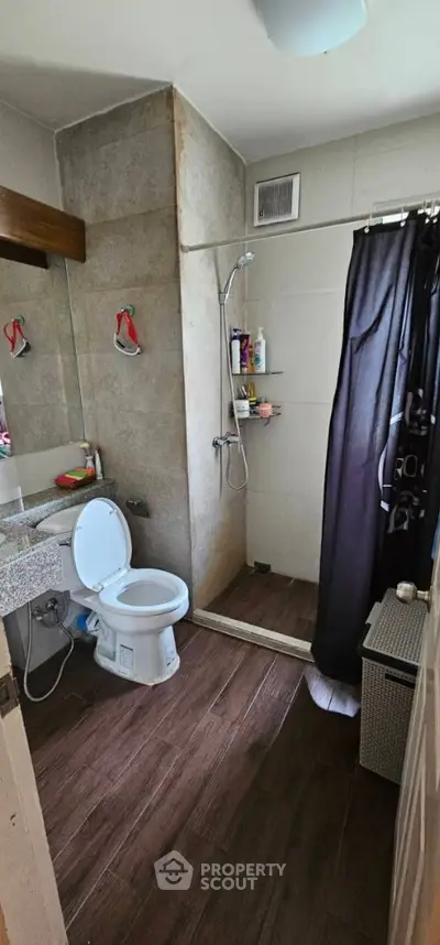 Modern bathroom with shower and wooden flooring in a stylish apartment.