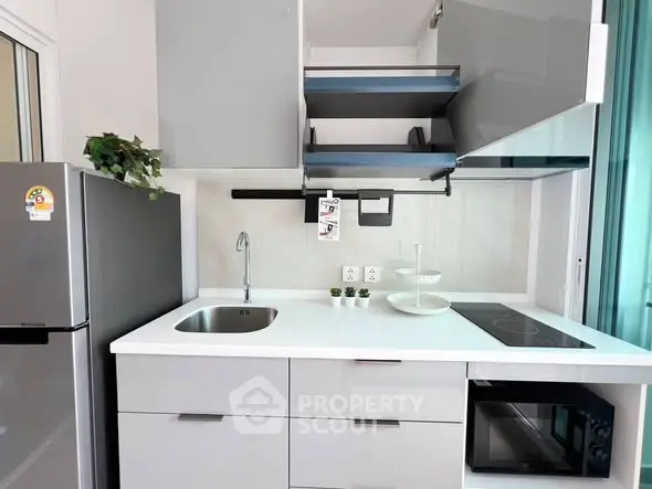 Modern kitchen with sleek cabinets, induction cooktop, and stainless steel appliances in a stylish apartment.