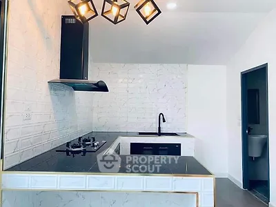 Modern kitchen with sleek black countertops and stylish lighting fixtures.