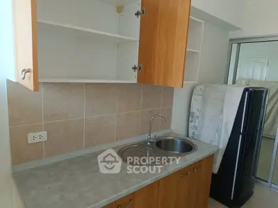 Compact kitchen with wooden cabinets and stainless steel sink in modern apartment.