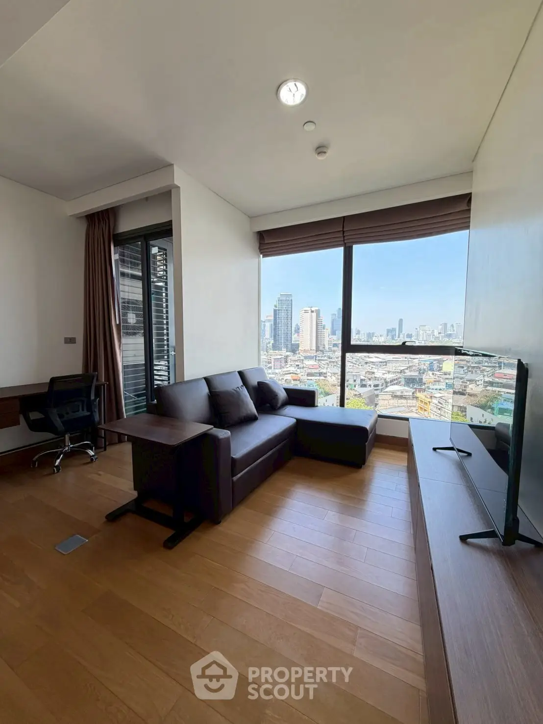 Modern living room with city view, featuring sleek furniture and large windows for natural light.
