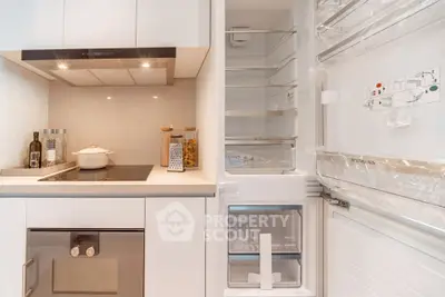 Modern kitchen with sleek appliances and open fridge showcasing ample storage space.