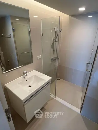 Modern bathroom with sleek glass shower and stylish vanity in contemporary apartment.