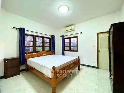 Spacious bedroom with wooden bed frame and large windows for natural light.