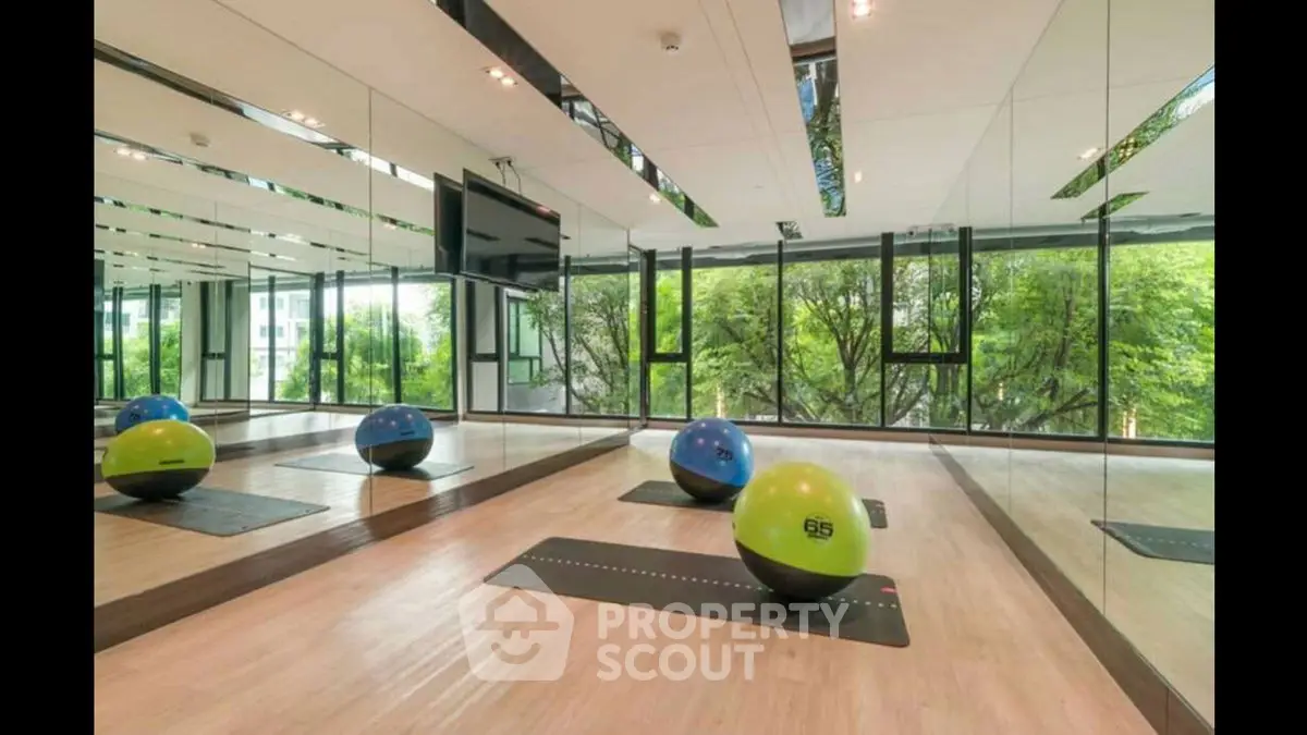 Modern gym with mirrored walls and exercise balls in a bright, airy space.