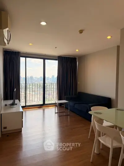 Spacious living room with city view and modern furniture in high-rise apartment.