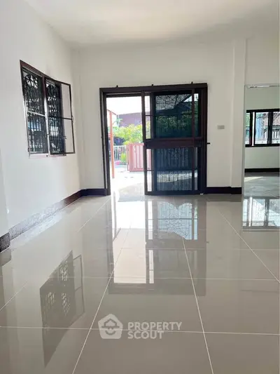 Spacious living room with glossy tiled floors and large windows offering natural light.