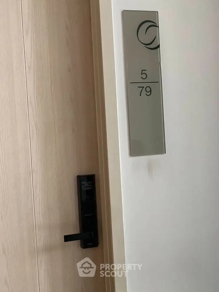 Modern apartment door with sleek handle and room number signage, showcasing contemporary design.