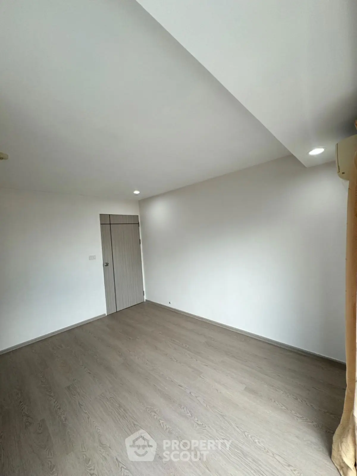 Spacious empty room with wooden flooring and modern lighting, ideal for customization.