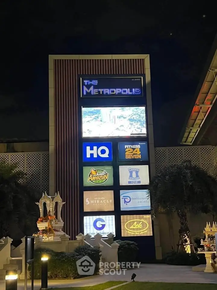 Illuminated commercial building signage at night showcasing various business logos.