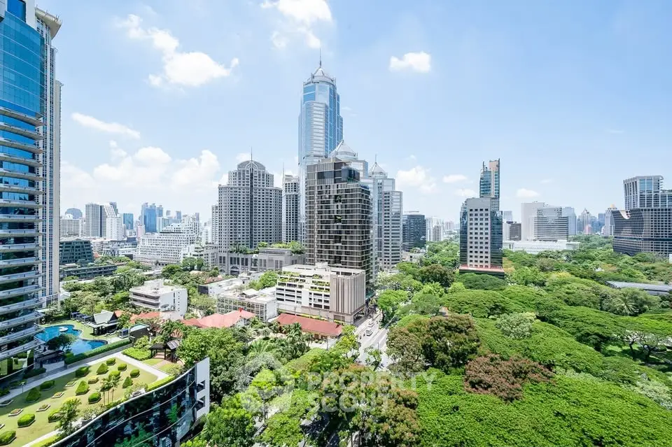 Stunning cityscape view with lush greenery and modern skyscrapers under a clear blue sky.