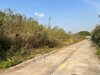 Expansive land plot with potential for development, featuring lush greenery and clear skies.