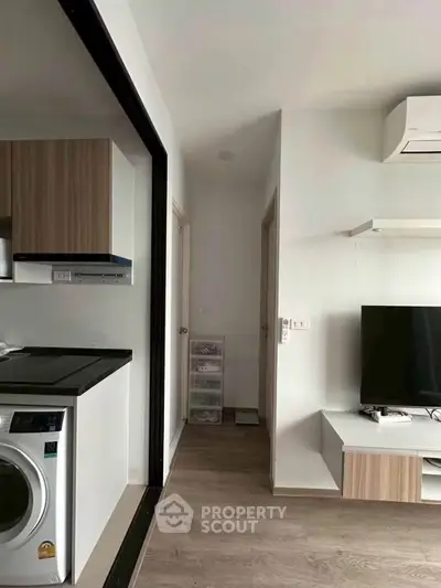 Modern apartment interior with washing machine and TV, showcasing sleek design and efficient use of space.