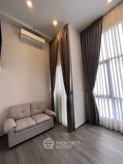 Modern living room with high ceilings, elegant curtains, and cozy sofa in a stylish apartment.