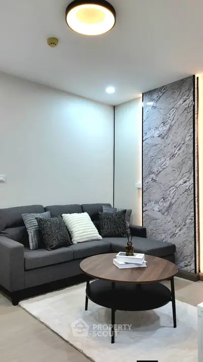 Modern living room with stylish gray sofa and round wooden coffee table on a plush rug.