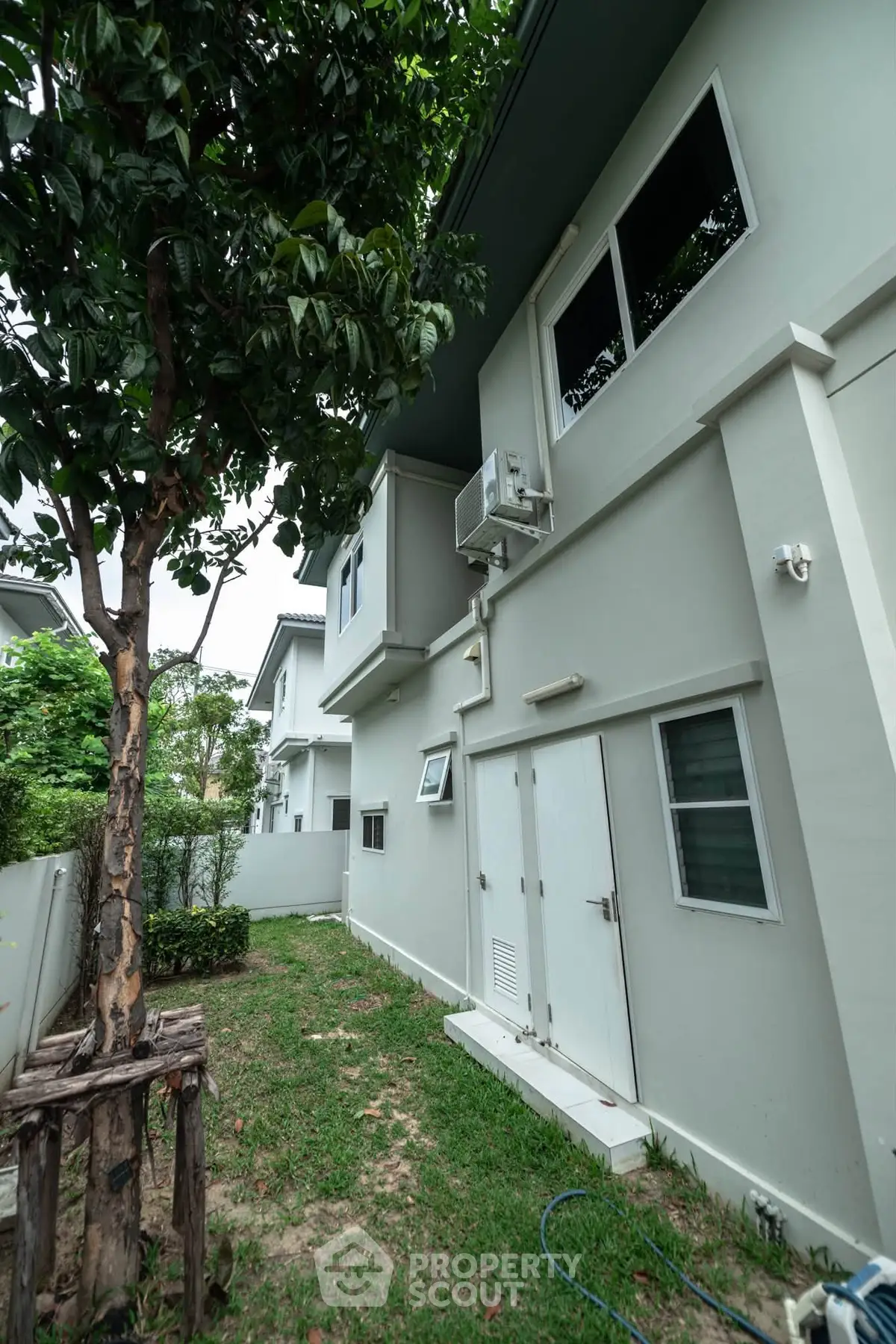 Modern two-story home exterior with lush garden and air conditioning unit