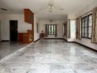 Spacious living room with marble flooring and large windows for natural light.