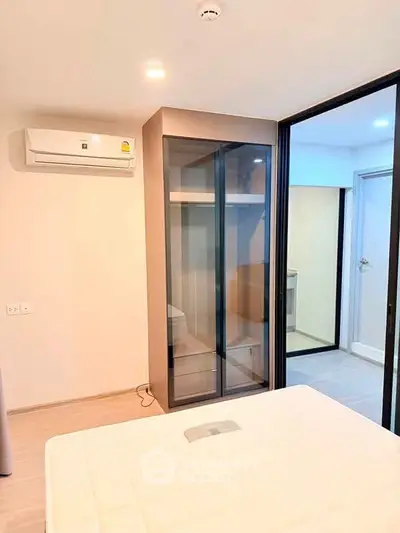 Modern bedroom with sleek glass wardrobe and air conditioning unit