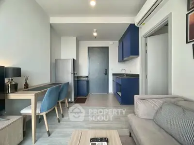 Modern living room with sleek blue kitchen cabinets and cozy dining area.