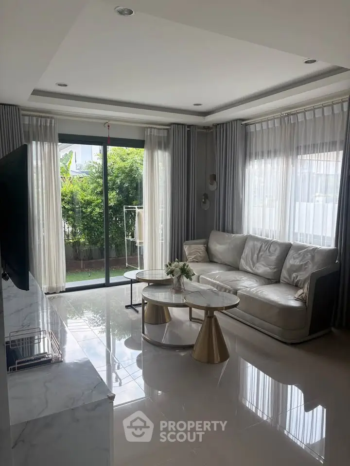 Elegant living room with modern decor and garden view, featuring a luxurious sofa and stylish coffee table.