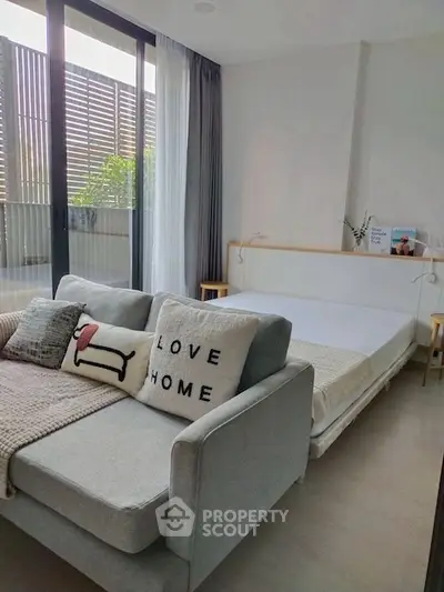 Cozy modern bedroom with stylish sofa and large windows opening to a private balcony.