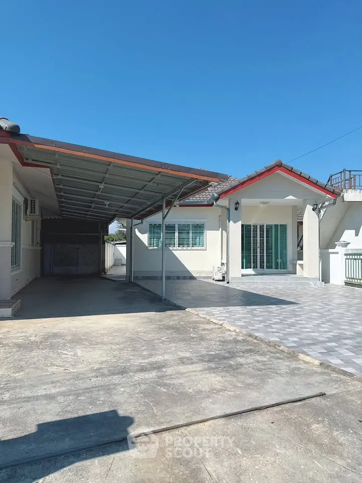 Spacious single-story home with carport and ample driveway space under clear blue skies.
