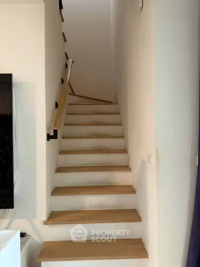 Modern staircase with wooden steps and sleek handrail in contemporary home