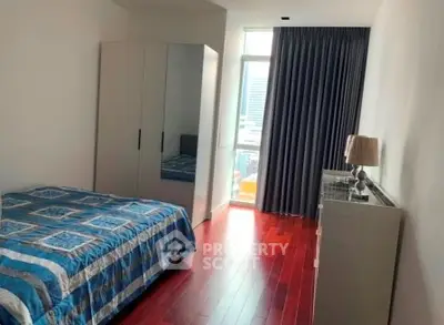 Modern bedroom with hardwood floors and large window in a stylish apartment.