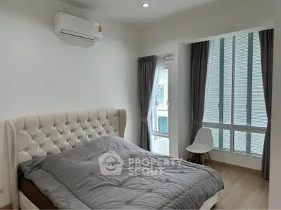 Modern bedroom with plush bed and large window, featuring elegant curtains and a cozy atmosphere.
